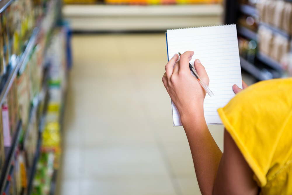 Cropped image of woman checking list at supermarket